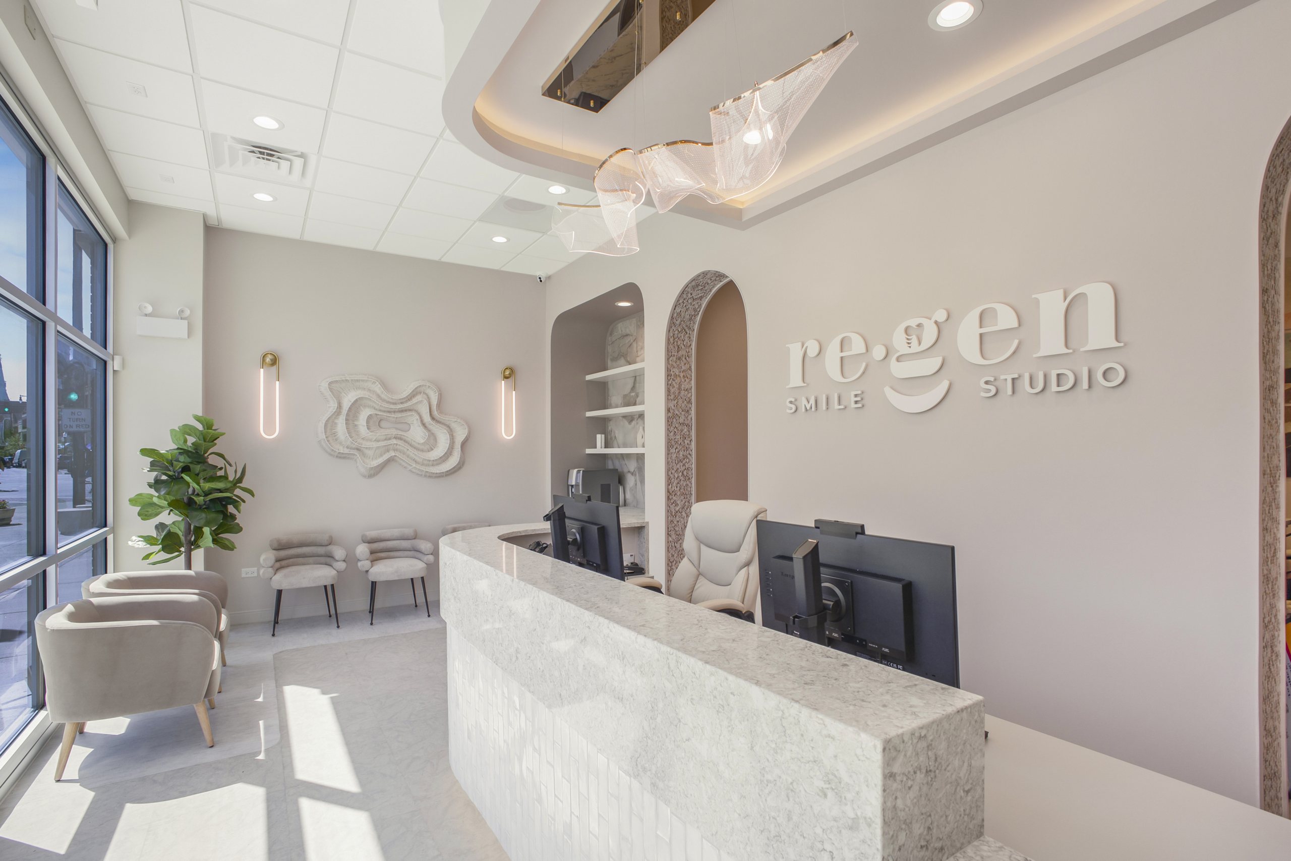 Reception at Re·gen Smile Studio in window light: the stone desk, the arches and the wordmark