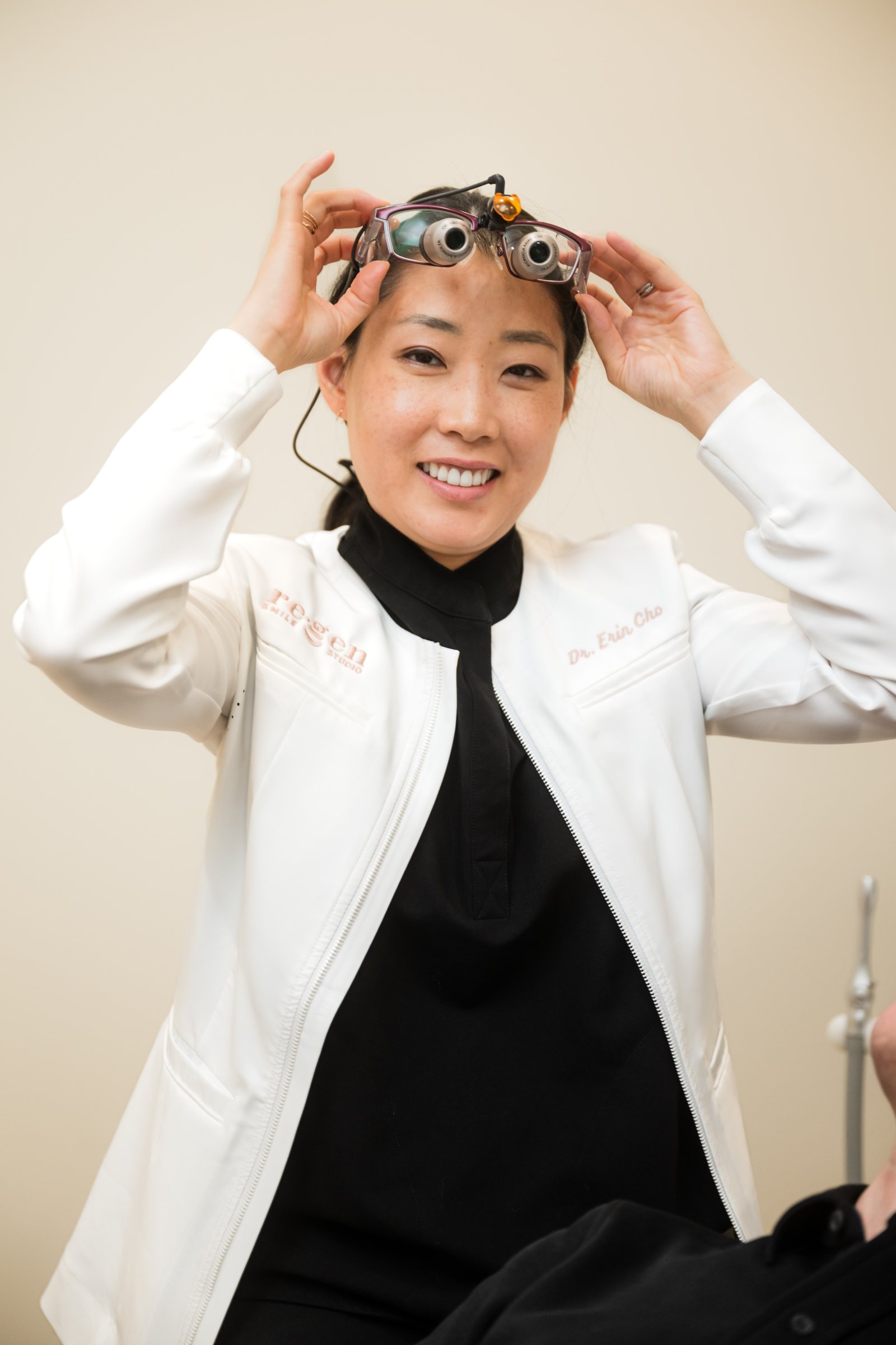 Dr. Erin Cho smiling as she lifts her loupes