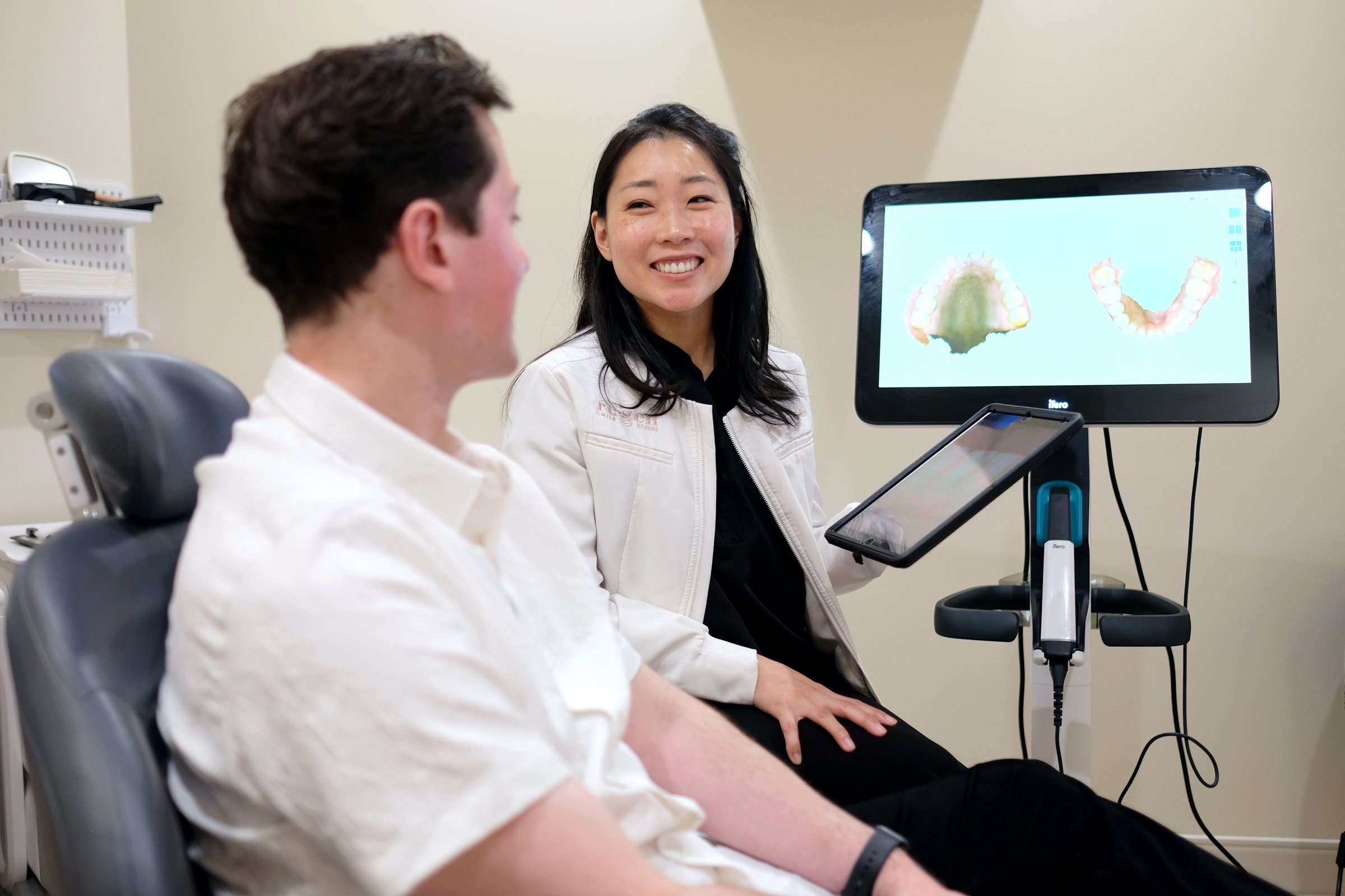 Dr. Erin Cho sitting beside a patient, his digital scan on the screen