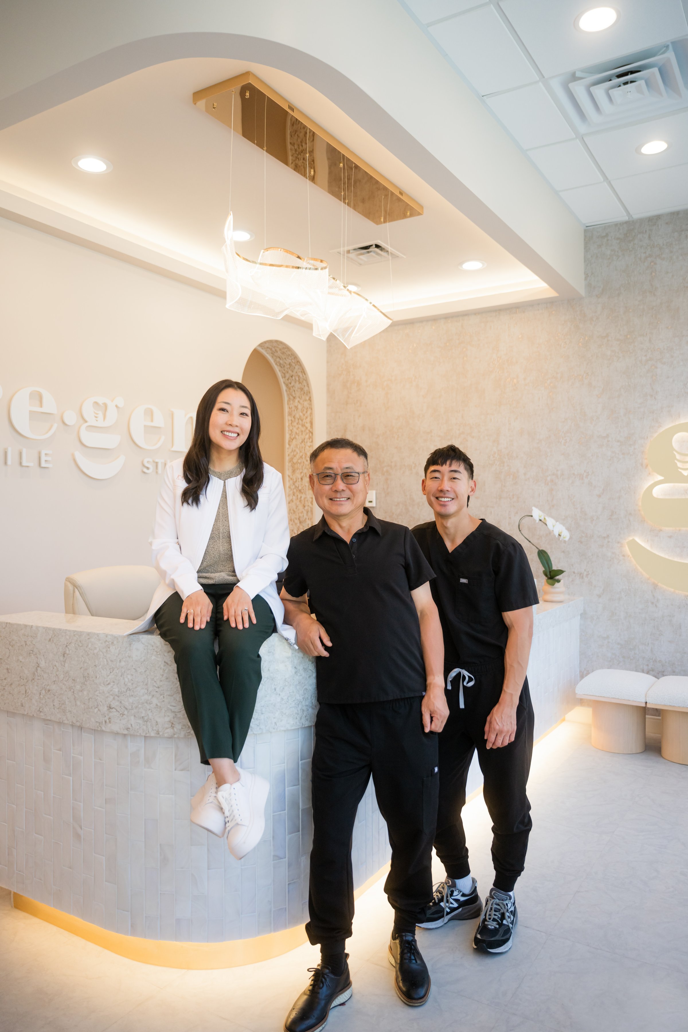 Dr. Erin Cho seated on the reception desk, her father and brother beside her