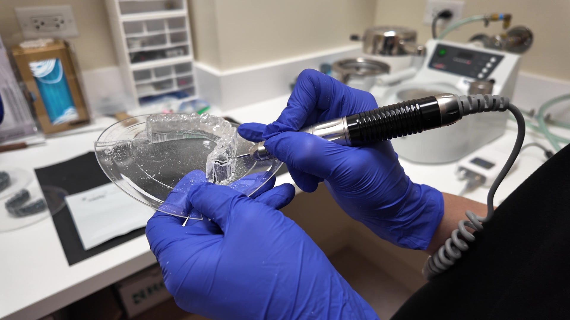 Gloved hands trimming a clear appliance to fit