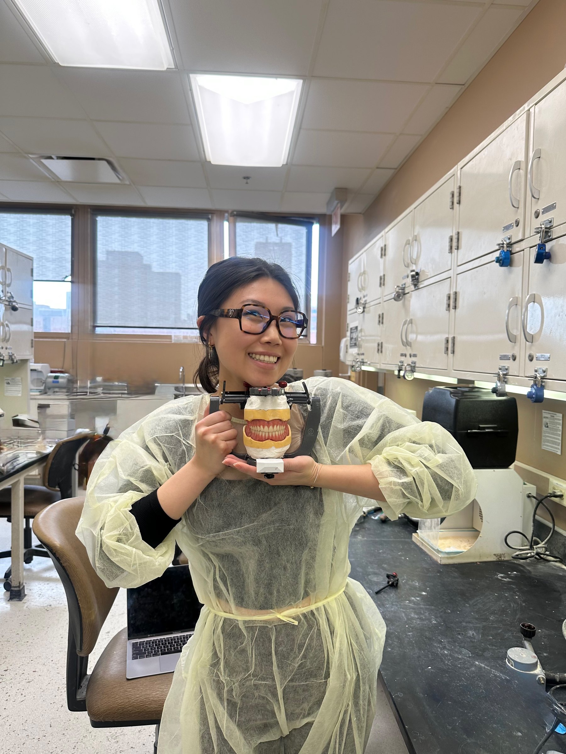 Dr. Ashley Choi in the dental school simulation lab, holding a model of teeth